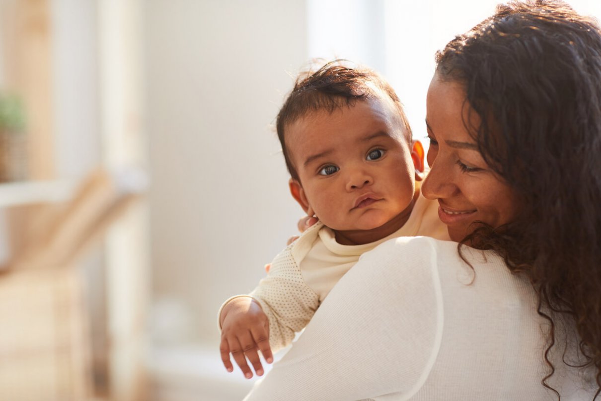 african motehr holding dark-skinned baby showing symptoms such as bilirubin