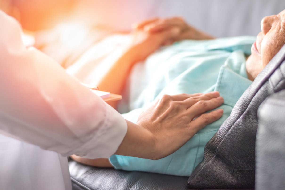 cancer patient laying in bed talking to his doctor