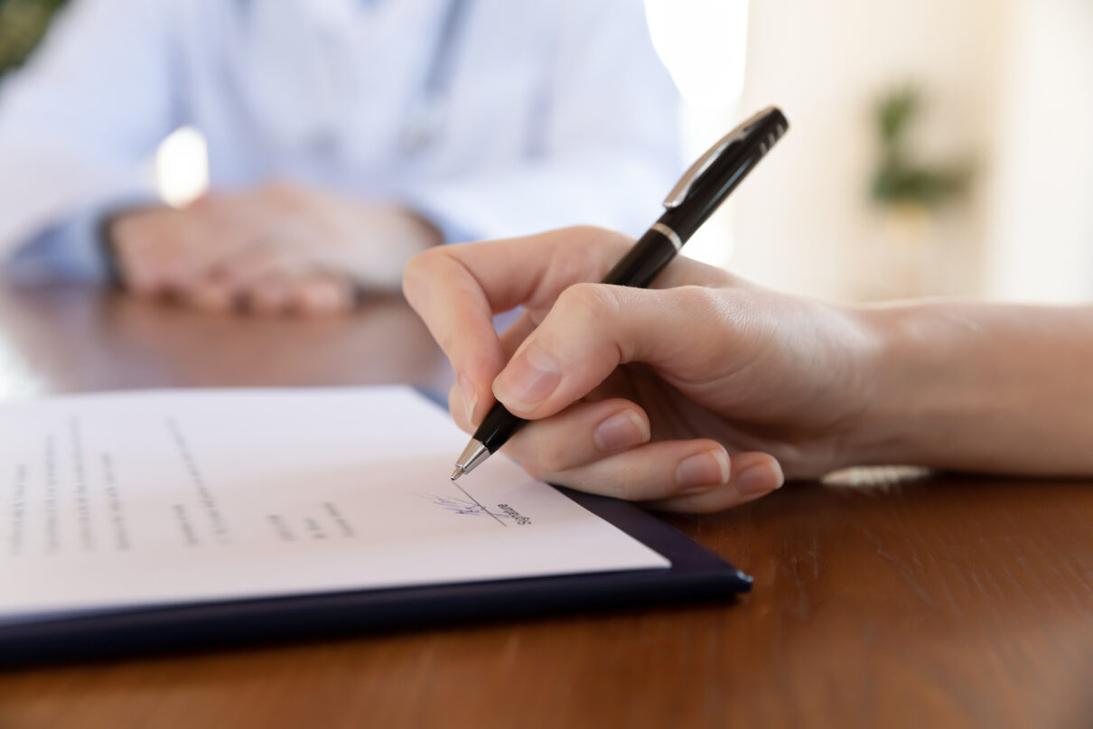 Female patient signing a medical informed consent in front of her doctor.